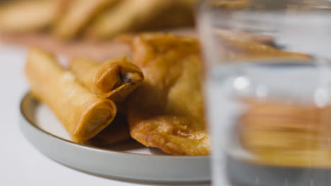 Close-Up-Of-Plate-Of-Samosas-And-Glass-Of-Water-On-Marble-Surface-Celebrating-Muslim-Festival-Of-Eid